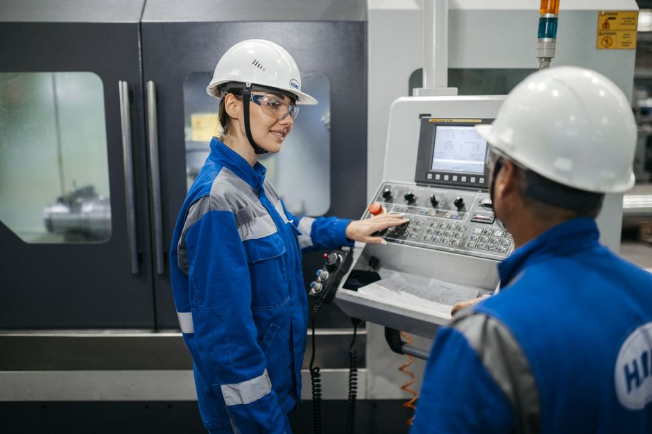 Industrial workers operating semiconductor manufacturing machinery in a controlled production setting, representing concentrated technology leadership.