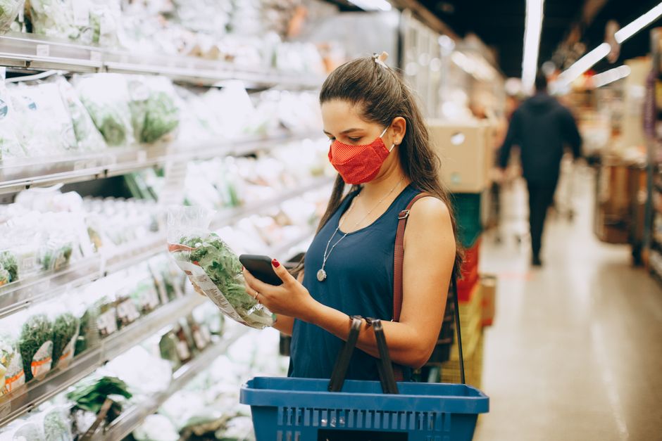 A shopper checking grocery prices in a supermarket aisle, representing consumer inflation and cost-of-living pressures