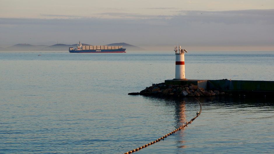 Container ship navigating a narrow international waterway at dawn