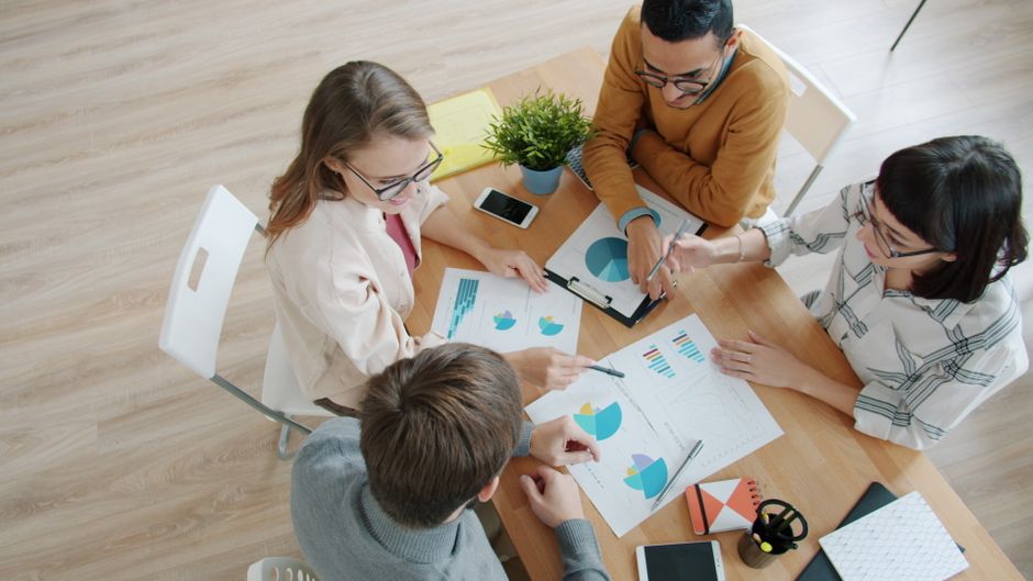 Professionals reviewing charts and market documents during an IPO analysis meeting.