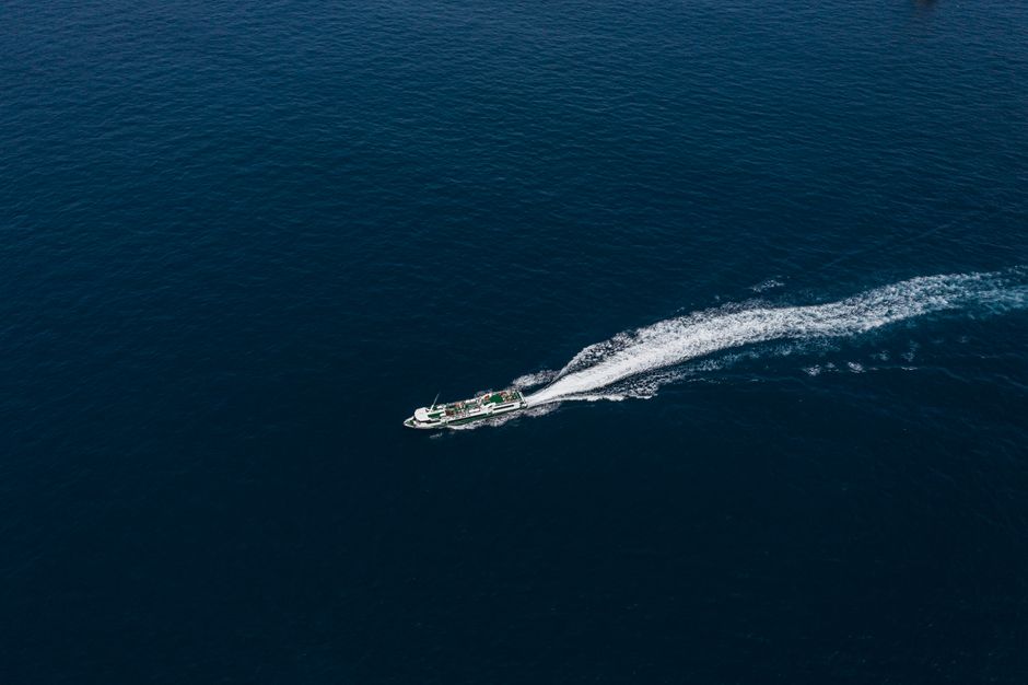 Aerial photo of a ship navigating through vast and calm ocean waters.