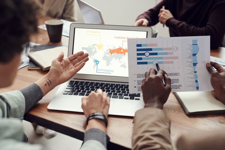 A team reviews cloud and market analytics on a laptop during a business meeting.