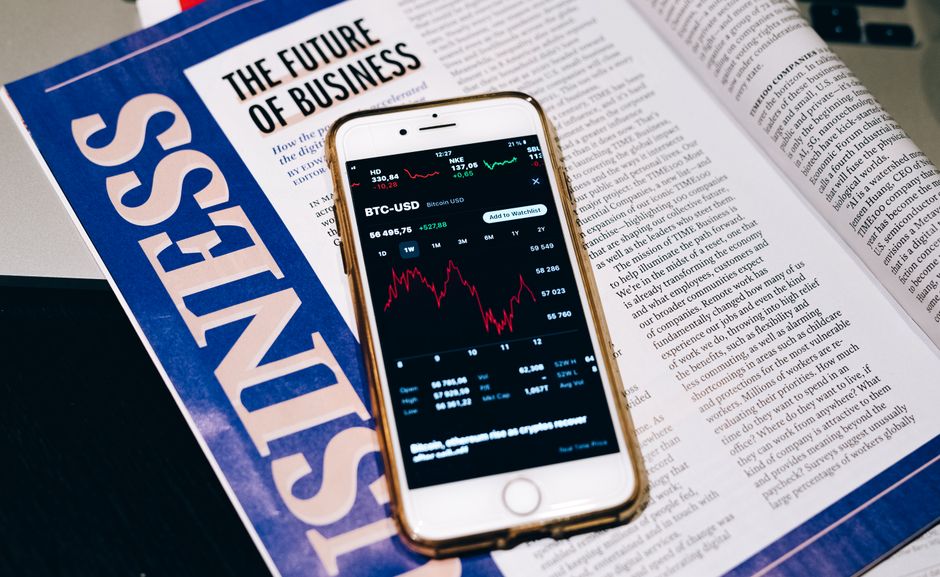 Smartphone displaying a financial chart beside a business magazine
