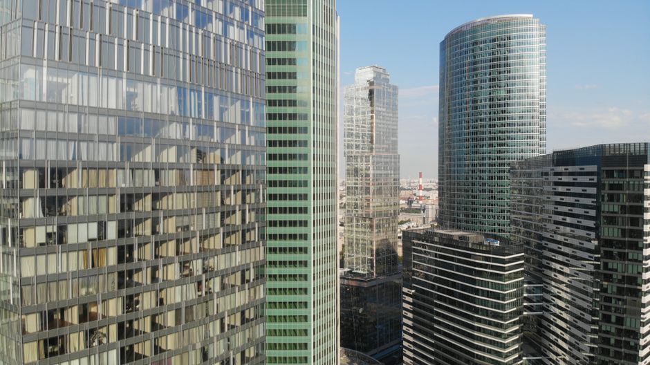 Contemporary skyscrapers with reflective glass facades under a clear blue sky, symbolizing the financial infrastructure of modern securities markets.