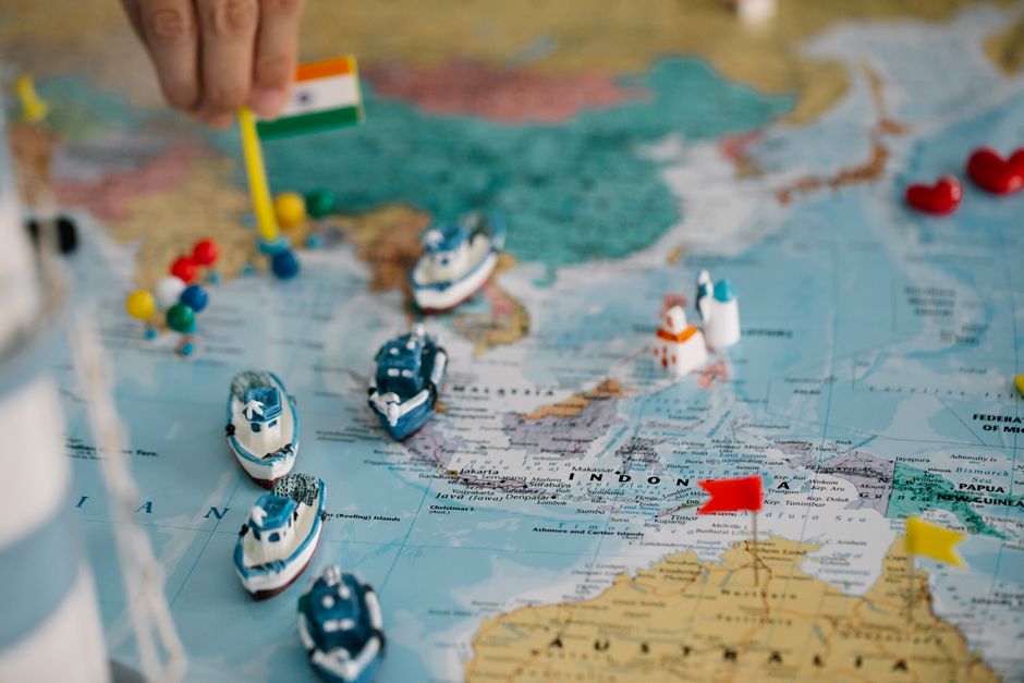 A world map with tiny model ships and flags indicating global trade routes
