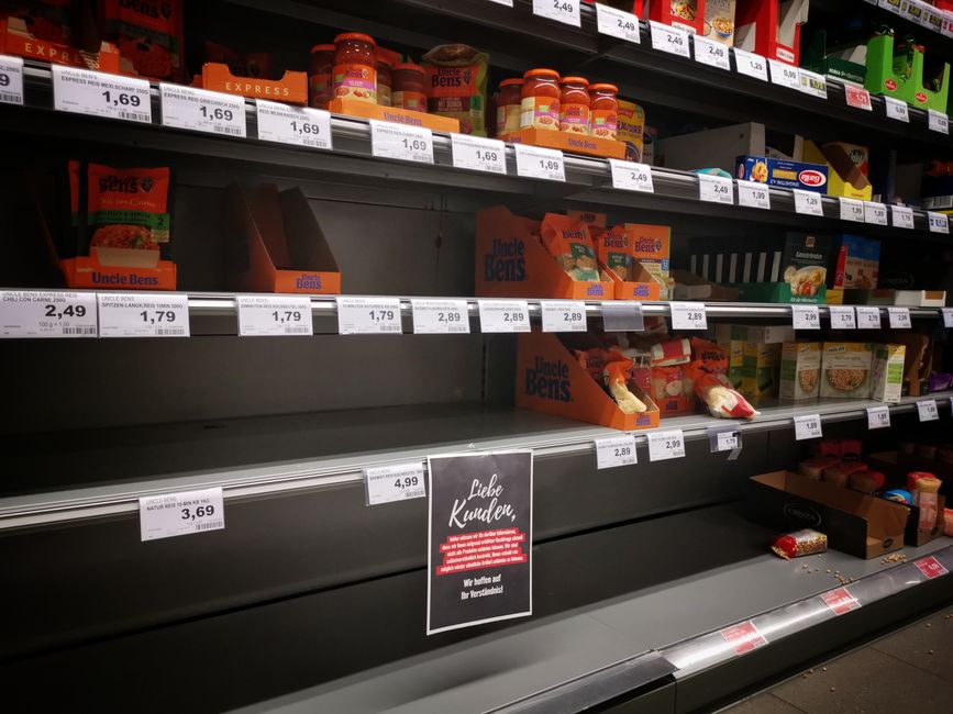 Partially emptied grocery store shelves with assorted packaged goods, reflecting the pressure household budgets face from persistent food inflation.