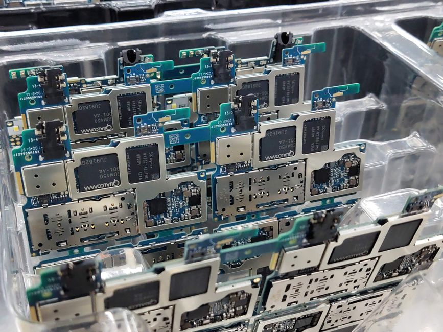 Smartphone circuit boards in a factory workshop, representing the electronics supply chain under memory-price pressure.