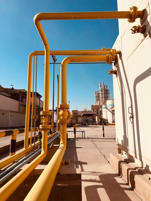 Yellow industrial gas pipeline under a clear blue sky at a Saudi facility.