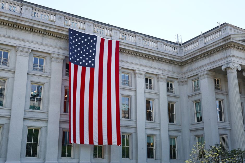 A large American flag hanging on a historic government building in Washington, D.C.