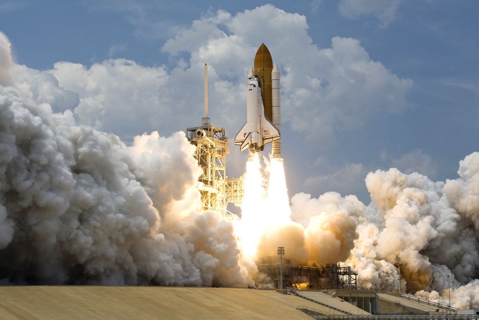 Space shuttle launching amid thick clouds of smoke