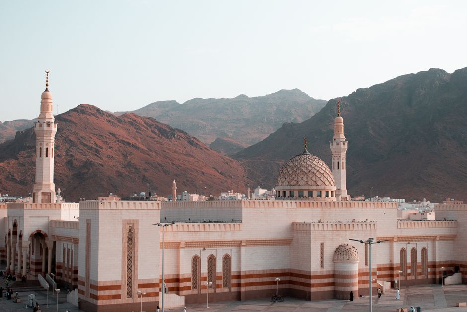 A mosque with minarets standing against a rugged mountain landscape in Saudi Arabia