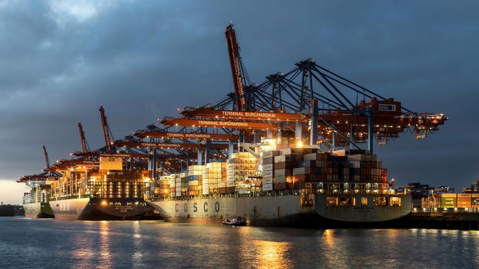 Container ships and port cranes illuminated at night, representing global maritime shipping