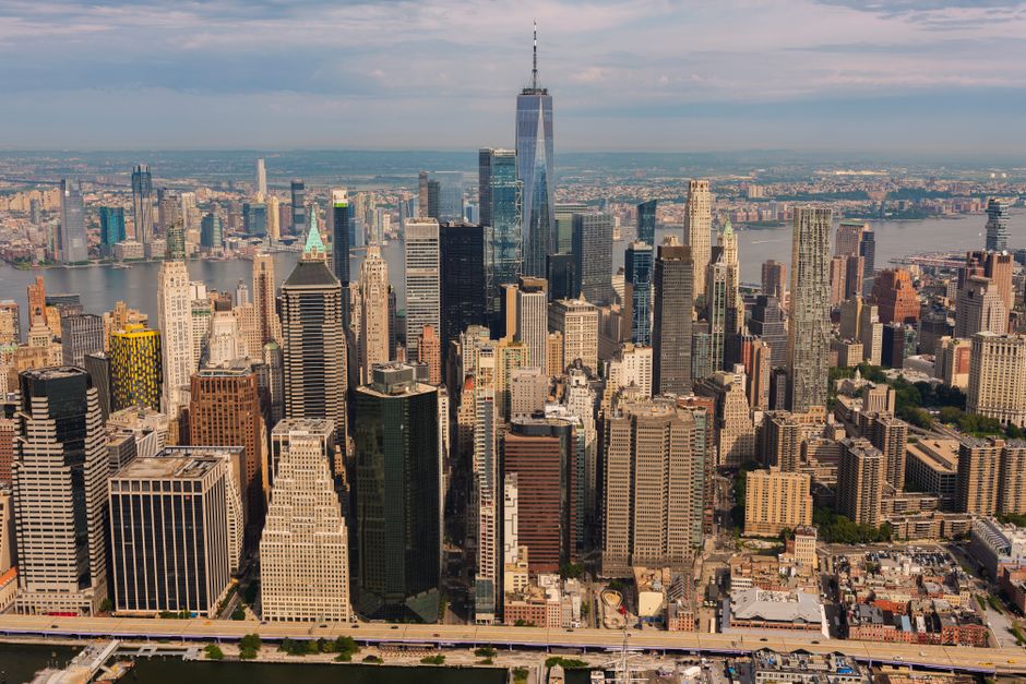 An aerial view of the New York City skyline featuring One World Trade Center under a clear sky.