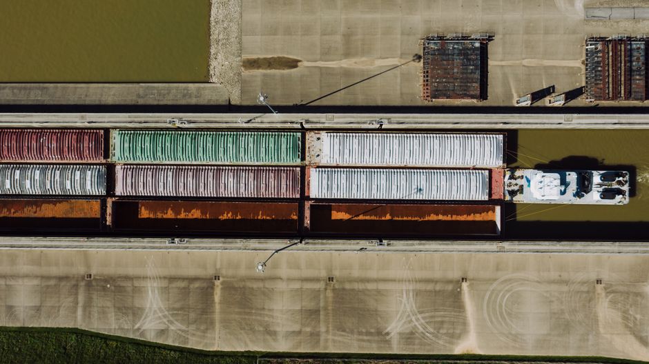 Aerial view of commercial cargo traffic moving through a narrow waterway, representing the shipping chokepoint now driving energy-market risk.