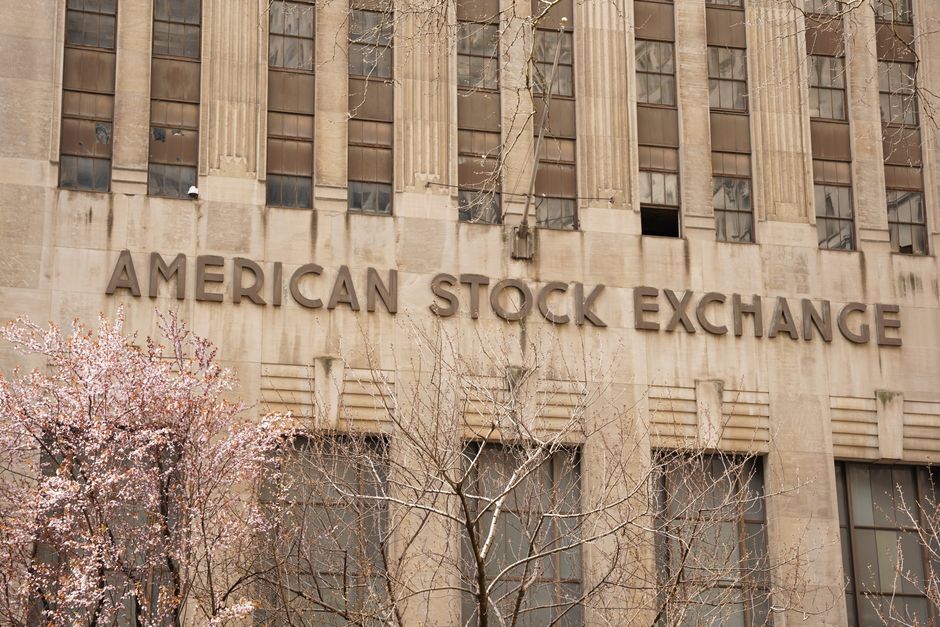 Facade of the American Stock Exchange Building in New York City during spring with blooming trees.