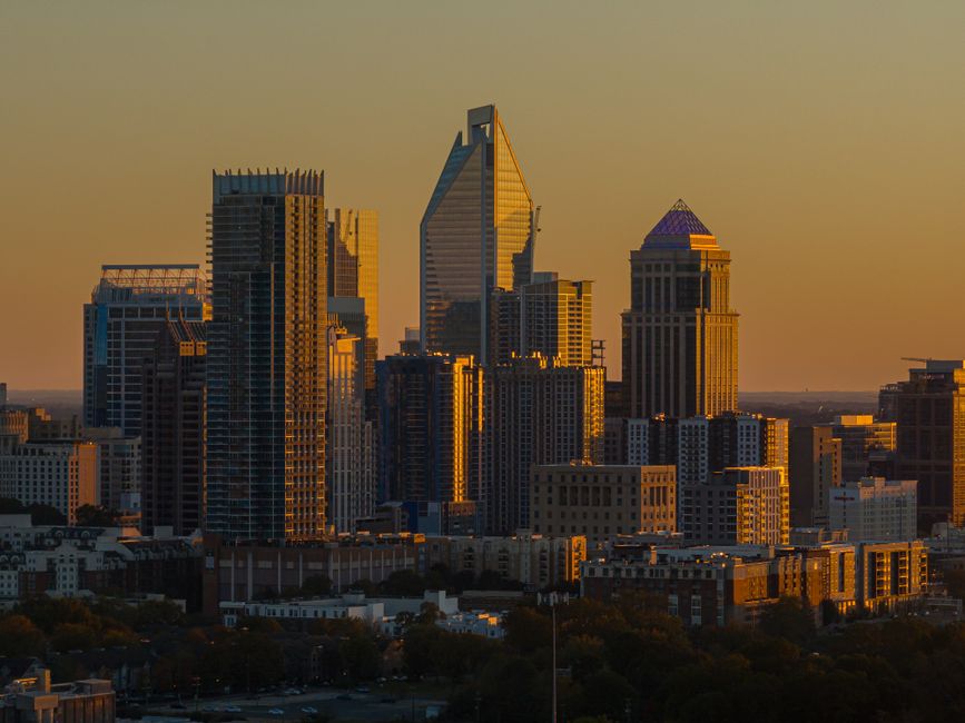 Modern financial district skyline illuminated at golden hour with skyscrapers silhouetted against a warm sunset sky.