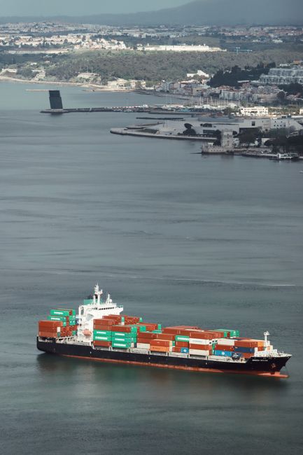Aerial view of a large cargo ship navigating a harbor, illustrating global shipping and trade routes.