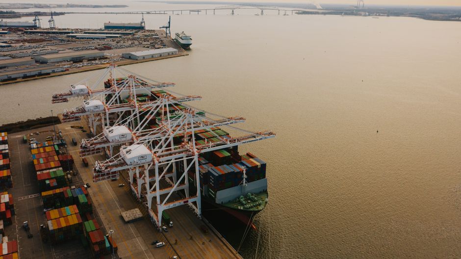 Container ship being loaded near cranes at a busy port