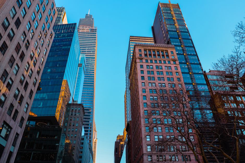 Low angle view of modern skyscrapers against a clear sky in a bustling urban financial district.