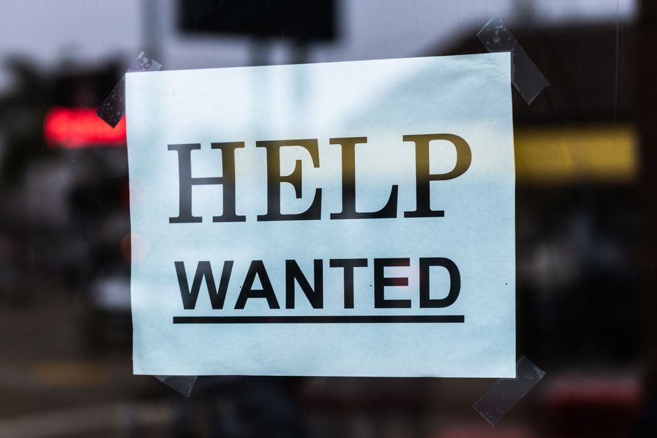 Help Wanted sign taped to a glass window