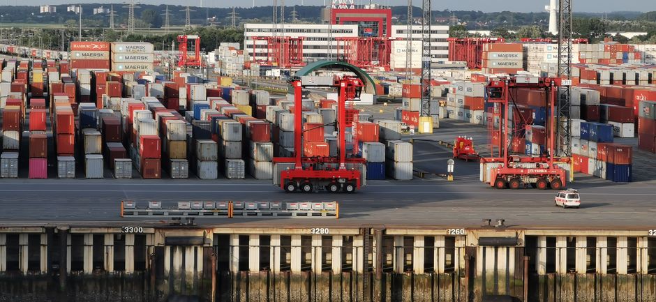 Cargo containers and cranes at a major port illustrate the maritime logistics risk at the center of current energy-market disruption.