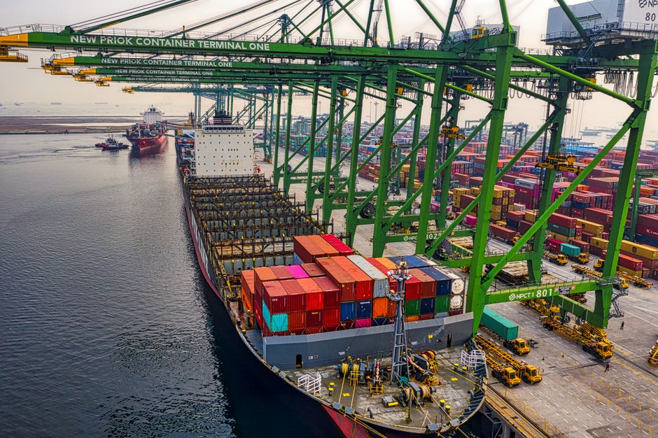 Container ship and port terminal with gantry cranes, representing global trade and maritime supply chain disruption.