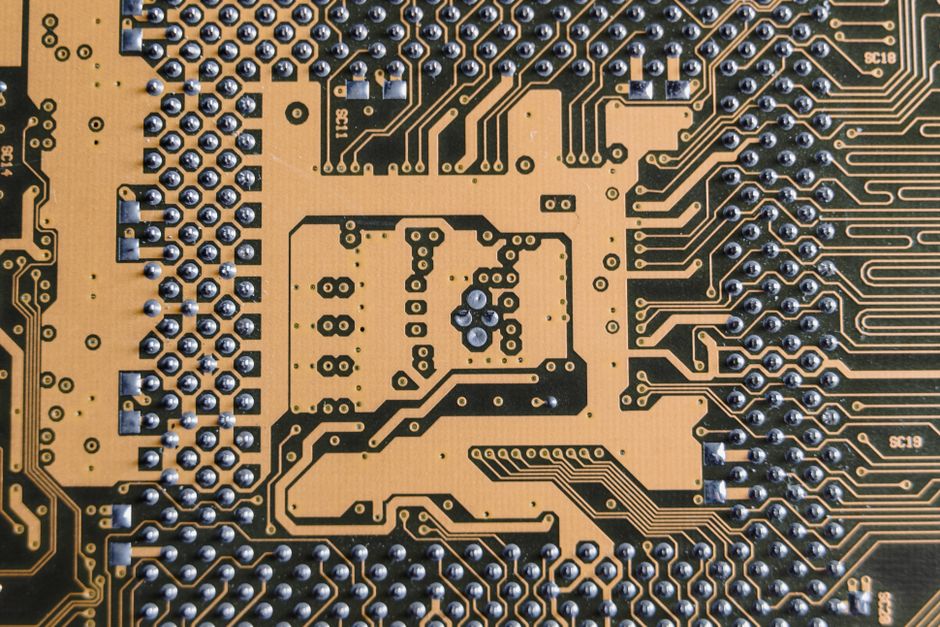 Close-up of a circuit board showcasing intricate patterns and metallic connections, representing the semiconductor infrastructure behind the AI buildout.